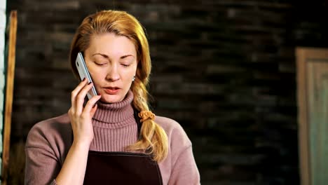 Florist-Frau-hinter-der-Theke-am-Telefon-zu-sprechen-und-mit-Blick-auf-das-Tablet.