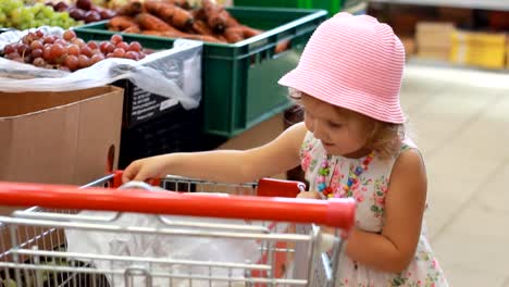 Child-girl-in-the-store-chooses-fruit.-Grocery-supermarket-and-shopping-trolley.