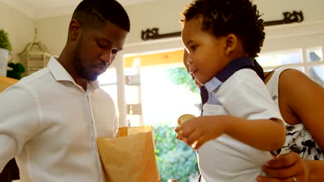 Side-view-of-young-black-family-looking-in-grocery-bag-in-kitchen-of-comfortable-home-4k