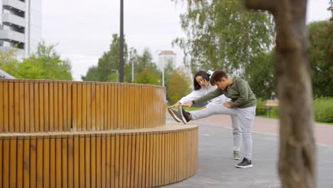 Asiatische-Mutter-und-Sohn-Stretching-Beine-vor-laufen-im-Freien