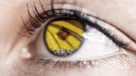 Woman-green-eye-in-close-up-with-the-flag-of-New-Mexico-state-in-iris,-united-states-of-america-with-wind-motion.-video-concept