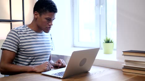 Junge-schwarze-Mann-verärgert-durch-Verlust,-am-Laptop-arbeiten