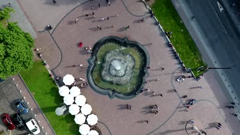 An-aerial-shot-of-a-fountain-on-an-avenue-along-which-people-walk