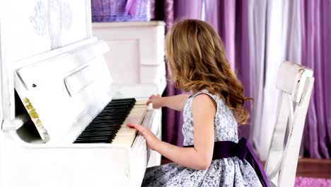 niña-rubia-juega-piano,-muchacha-en-un-vestido-con-un-cinturón-púrpura,-de-4k