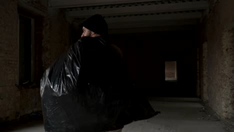 Dirty-homeless-with-garbage-bag-walks-in-abandoned-building