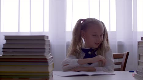 Portrait-school-girl-girl-having-fun-and-dancing-at-table-with-textbooks-stack