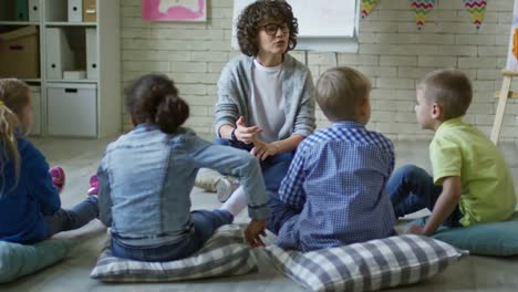 Maestra-de-Kindergarten-femenino-contando-la-historia-a-los-niños