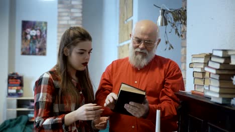 Grandfather-and-granddaughter-discusses-book-standing-near-the-the-piano