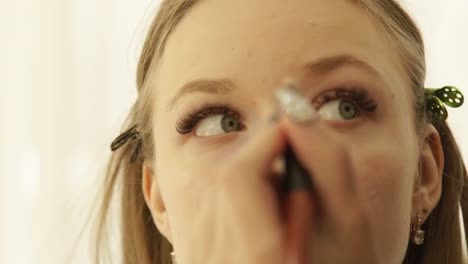 Close-up-face-young-woman-during-applying-makeup-with-cosmetic-brush-on-skin.-Visagiste-applying-tone-cream-on-skin-beauty-model-during-makeup-lesson-in-beauty-school