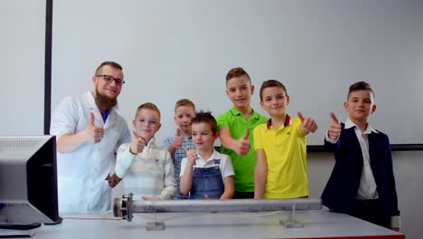 Children-and-laboratory-assistant-shows-thumbs-up-to-camera