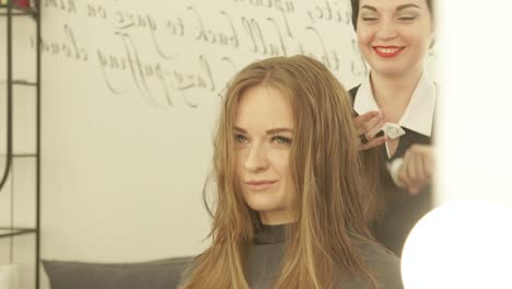 Estilista-peinando-el-pelo-de-hebra-antes-de-secar-con-el-secador-de-peluquería.-Cerrar-haircutter-cabello-largo-con-cepillo-para-el-pelo-después-de-lavar-y-cortar-en-salón-de-belleza