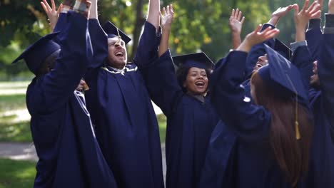 happy-students-in-mortar-boards-with-hands-on-top