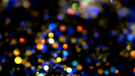 Defokussierten-schillernden-bunten-Glitter-Konfetti,-schwarzer-Hintergrund.-Urlaub-abstrakte-festliche-Bokeh-Lichtpunkte.