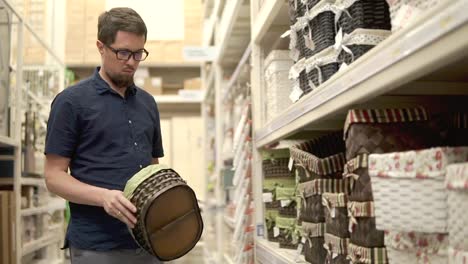 Man-is-taking-different-woven-baskets-from-racks-in-a-shop,-choosing