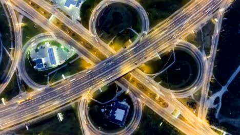 Estática-vertical-descendente-vista-aérea-de-tráfico-en-el-intercambio-de-la-autopista-por-la-noche.-Fondo-de-timelapse