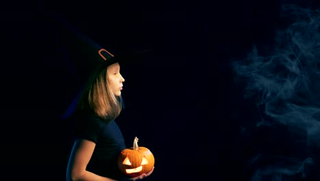 Girl-wearing-black-witch-hat-holding-jack-o'-lanterns