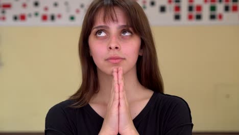 Portrait-of-young-female-keeping-palms-together-believing-in-good-luck-or-being-glad-or-praying-to-God.