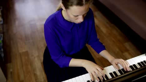 Teen-girl-plays-on-the-keyboard-of-the-digital-piano.