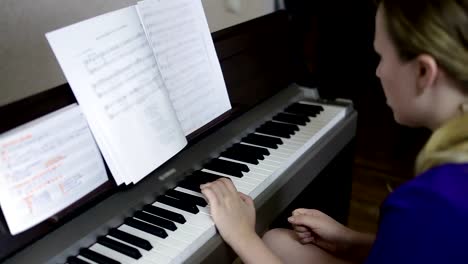 Teen-girl-plays-on-the-keyboard-of-the-digital-piano.