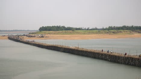 Traffic-jam-on-the-bamboo-bridge-over-the-Mekong-River.-Motorbikes,-bicycles,-and-people-on-foot-crossing-it-(-time-lapse)