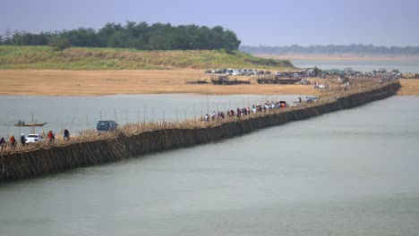 Stau-auf-der-Bambusbrücke-über-den-Mekong-Fluss.-Motorräder-und-Autos-überqueren.-Das-kleine-Fischerboot,-unter-der-Brücke