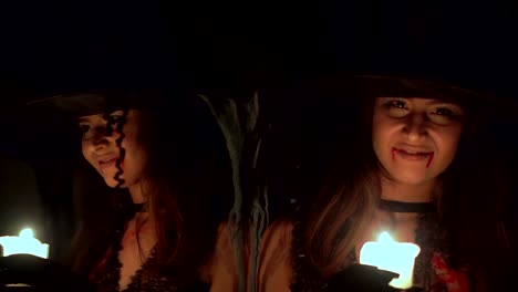 Halloween-witch-in-the-dark-near-the-mirror-with-a-candle.-She-is-looking.