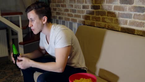 Man-drinks-beer-and-chips-in-front-of-TV