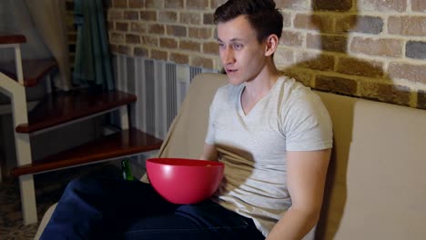 Handsome-man-with-a-beer-and-chips-in-front-of-TV