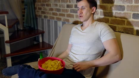 Young-man-with-beer-and-chips-in-front-of-TV