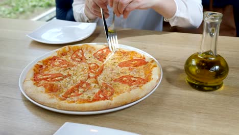 Pizzeria.-Junge-Frau-nimmt-ein-Stück-Pizza-in-ihrem-Teller