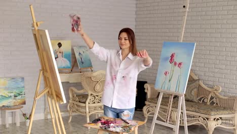 Happy-artist-with-a-dirty-rag-in-her-hands-is-spinning-in-the-Studio-for-drawing