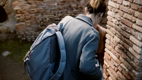 Two-tourists,-young-woman-and-older-man,-enjoying-exploring-old-ruins-of-Ostia-Antica-in-Italy-during-vacation-trip.