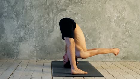 Deportivo-yogui-joven-musculoso-hombre-haciendo-Wide-Legged-hacia-adelante-de-la-curva,-postura-Prasarita-Padottanasana-(Dandayamana-Bibhaktapada-Paschimotthanasana