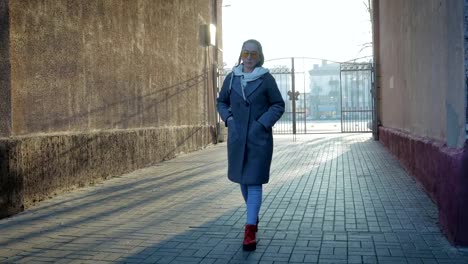 Eine-Frau-zu-Fuß-in-einen-Mantel-in-der-Stadt-im-Herbst-oder-Frühling