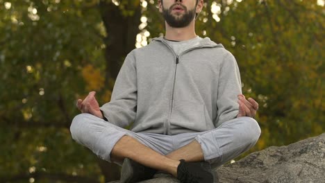 Sportive-man-sitting-in-lotus-position-on-rock-top,-meditation-and-relax,-hobby
