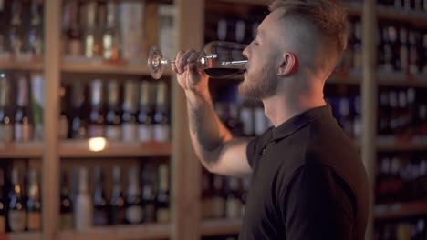 Retrato-de-hombre-guapo-en-perfil-admirando-vino-en-el-cristal.-Hombre-sabe-a-bebida-alcohólica-y-lo-ama.-El-cliente-es-en-la-tienda-de-alcohol