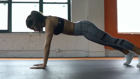 Atlética-bella-deportiva-sexy-joven-empuja-hacia-arriba-el-ejercicio-intensivo-de-entrenamiento-en-el-gimnasio-de-entrenamiento.-Cámara-lenta.