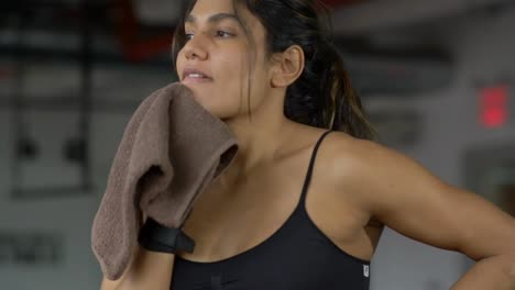 Healthy-young-beautiful-fit-woman-wiping-sweat-with-towel-after-intensive-exercise-workout-in-fitness-gym.-Shot-in-slow-motion.