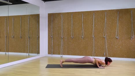 Mujer-joven-que-se-extiende-en-el-estudio-de-yoga-con-espacio-de-copia