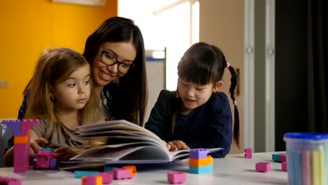 Girls-with-teacher-looking-at-picture-book-at-class