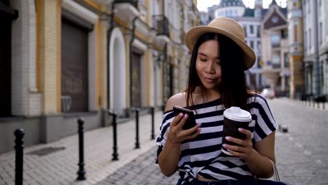 Carefree-girl-with-cellphone-walking-along-street