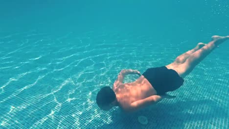 Young-guy-swims-underwater-in-a-swimming-pool