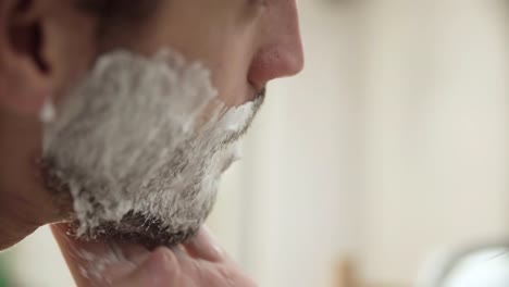 Higiene-de-los-hombres.-Aplicación-de-espuma-de-afeitar-en-Closeup-barba-hombre