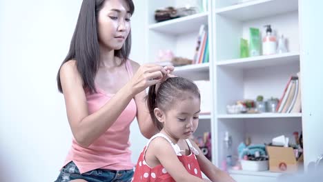 Mother-and-daughter-dress-and-comb-hair-in-the-house.