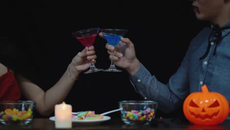 Couple-in-Halloween-costume-celebrating-with-glass-of-liquor-in-Halloween-night-party