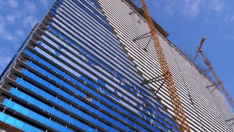 Kran-auf-einer-Baustelle-gegen-den-blauen-Himmel-baut-einen-neuen-Wolkenkratzer.-Gebäudebau