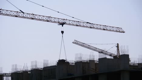 Turmkran-auf-einer-Baustelle-hebt-eine-Last-im-Hochhaus