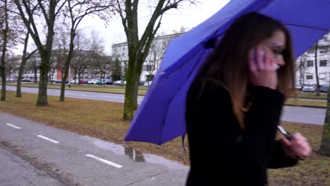 Junge-Frau-mit-Regenschirm-mit-Smartphone