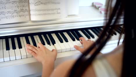 Young-brunette-woman-is-playing-piano-in-bright-room,-hand-held