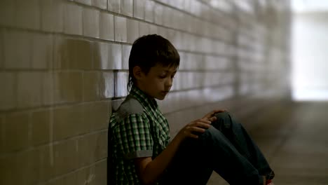 sad-lonely-battered-boy-sits-on-the-floor-in-a-tunnel-in-deep-depression-looking-at-the-camera,-no-one-is-waiting-for-the-boy-at-home